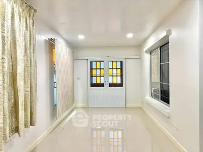 Spacious bright room with large windows and elegant curtains, perfect for versatile living space.