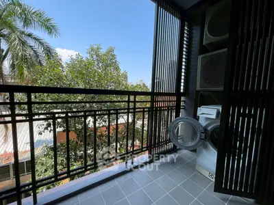 Charming balcony with lush greenery view and modern laundry setup, perfect for urban living.