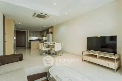 Spacious modern living room with open kitchen and dining area, featuring sleek furniture and neutral tones.