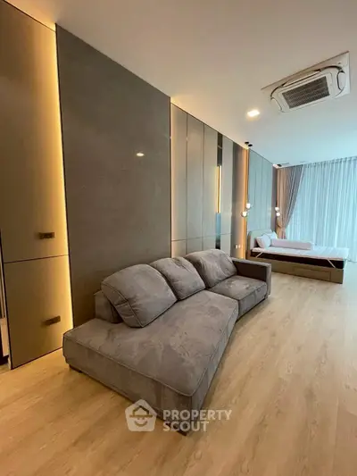 Modern living room with sleek design and cozy gray sofa, featuring elegant lighting and wooden flooring.