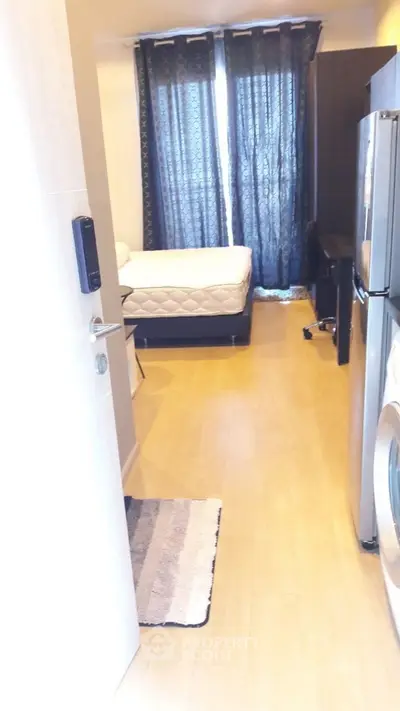 Cozy bedroom with natural light, featuring a bed, washing machine, and modern decor.