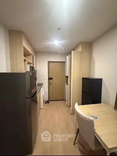 Modern kitchen with sleek appliances and cozy dining area in a compact apartment.