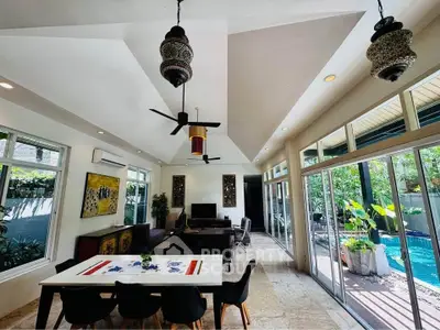 Spacious living room with modern decor and poolside view, featuring elegant lighting and open layout.