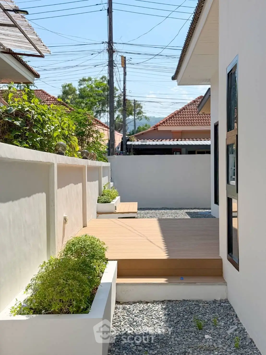 Charming exterior view of modern home with landscaped garden and wooden deck, perfect for outdoor relaxation.