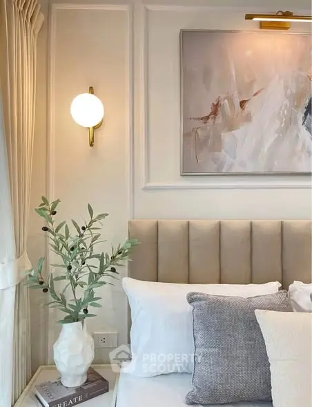 Elegant bedroom corner with plush headboard, modern art, and soft lighting for a cozy ambiance.