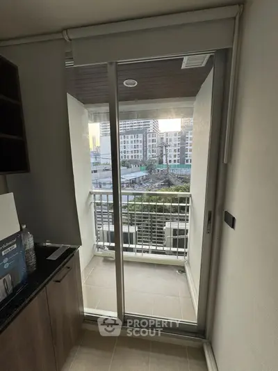 Modern apartment balcony with sliding glass door and urban view, perfect for city living.