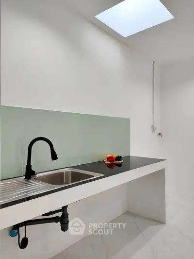 Modern minimalist kitchen with skylight and sleek black countertop