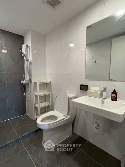 Modern bathroom with sleek design, featuring a shower, toilet, and sink in a stylish setting.