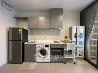 Modern kitchen with sleek appliances including washing machine and fridge, featuring open layout and stylish cabinetry.