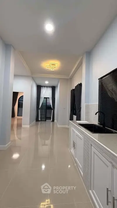 Spacious modern kitchen with sleek design and open layout, featuring elegant lighting and glossy tiled floors.