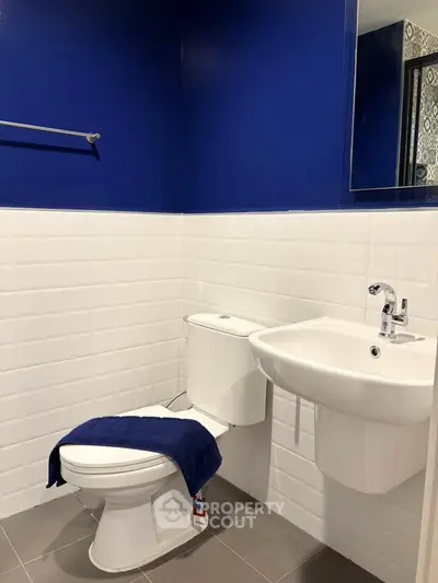 Modern bathroom with blue and white tiles, featuring a sleek sink and toilet.