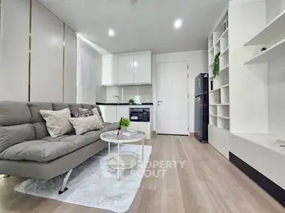 Modern living room with sleek kitchen, cozy sofa, and stylish decor in open layout apartment.