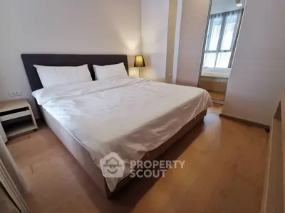 Spacious bedroom with modern decor and large mirror reflecting natural light.