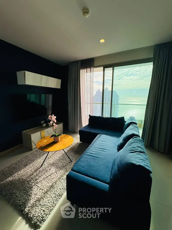 Modern living room with ocean view, featuring stylish blue sofa and sleek decor.