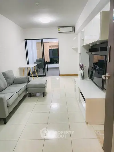 Modern living room with sleek furniture and tiled flooring, leading to a balcony.