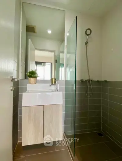 Modern bathroom with sleek glass shower and stylish vanity in contemporary apartment.