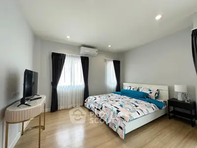 Spacious bedroom with modern decor and natural light, featuring a stylish bed and sleek TV setup.