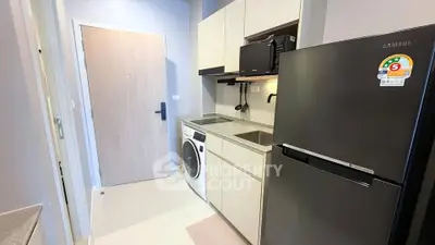 Modern kitchen with sleek appliances and washing machine in compact layout.