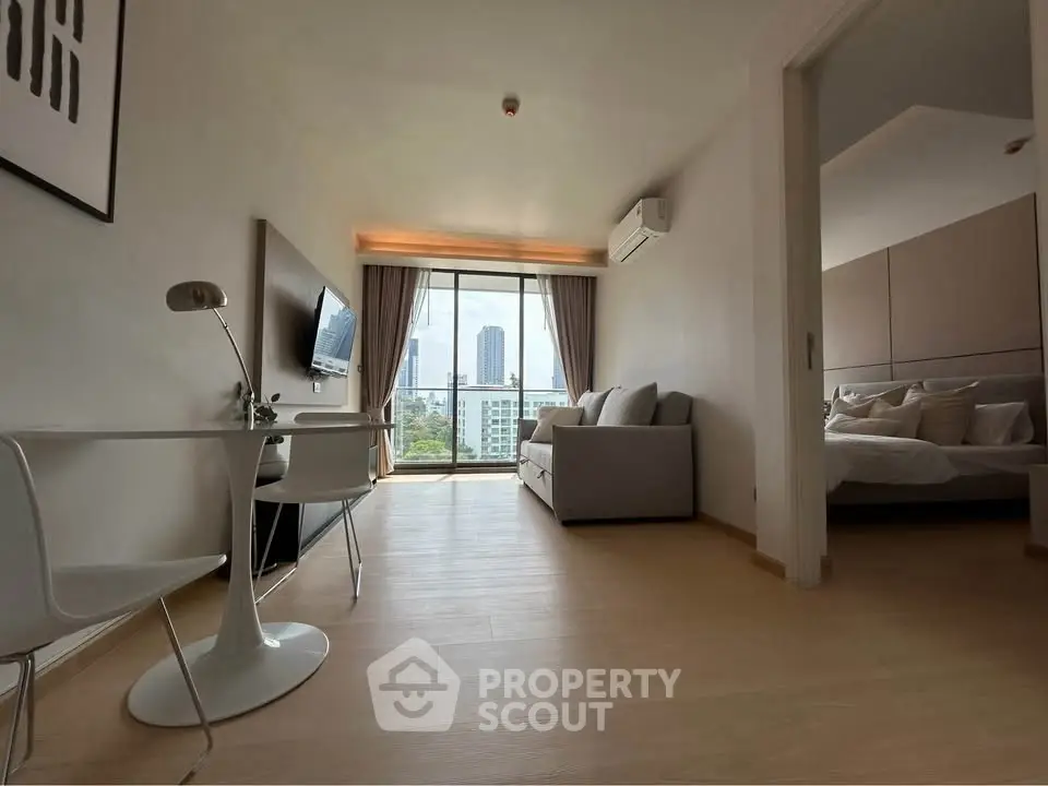 Modern apartment with open living room and bedroom, featuring city view and stylish decor.