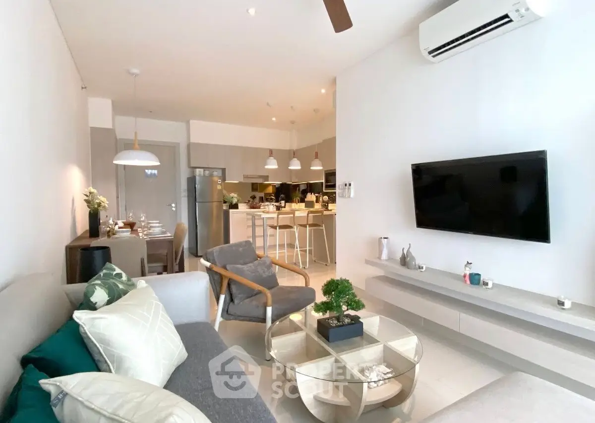 Modern living room with open kitchen, stylish decor, and cozy seating area.