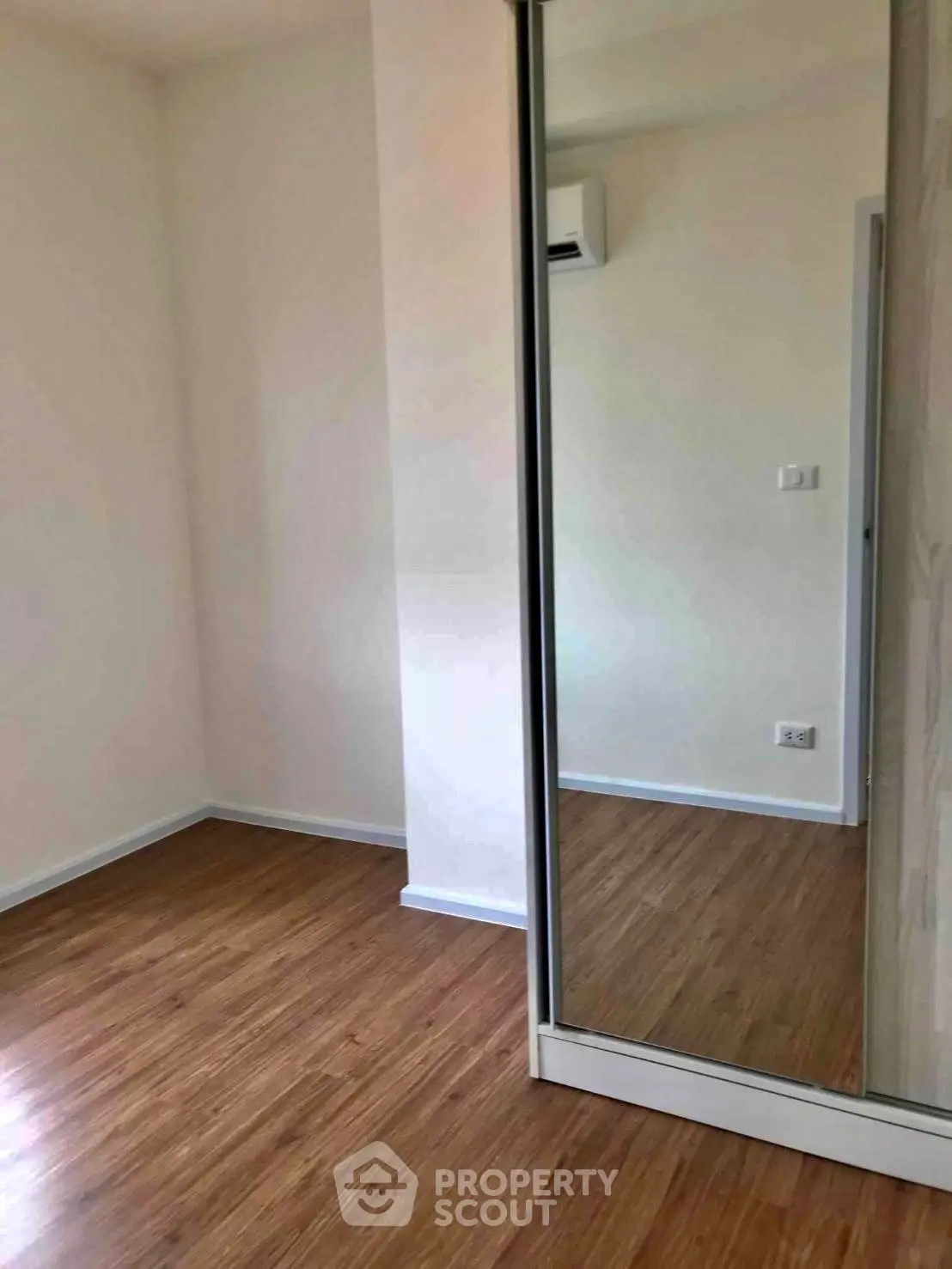 Spacious room with wooden flooring and mirrored closet in modern apartment.