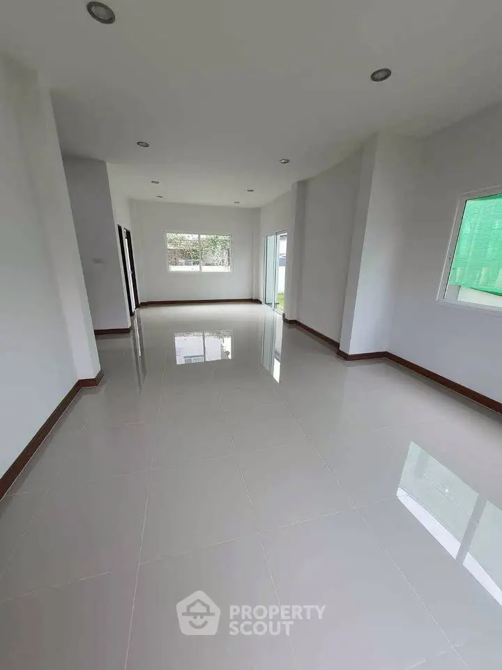 Spacious empty room with glossy tiled floors and large windows.