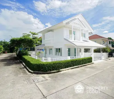 Charming two-story white house with lush greenery on a sunny day