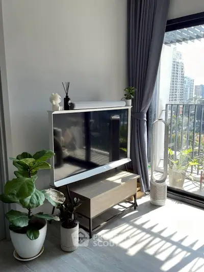 Modern living room with large TV, stylish decor, and balcony view in urban apartment.