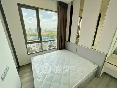 Modern bedroom with large window offering stunning city views, featuring a comfortable bed and stylish decor.