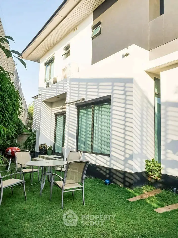 Charming modern house exterior with lush garden and outdoor seating area.