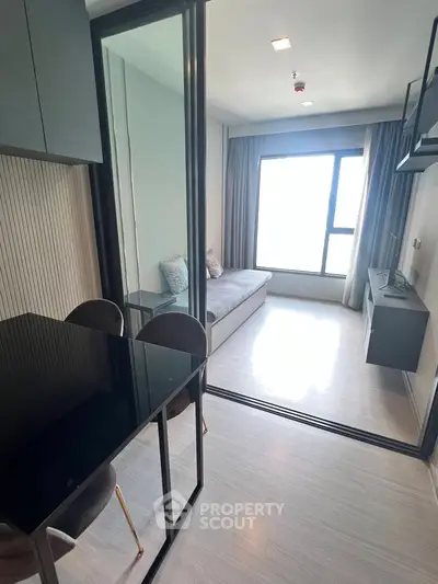 Modern living room with glass partition and sleek furniture in a bright apartment.