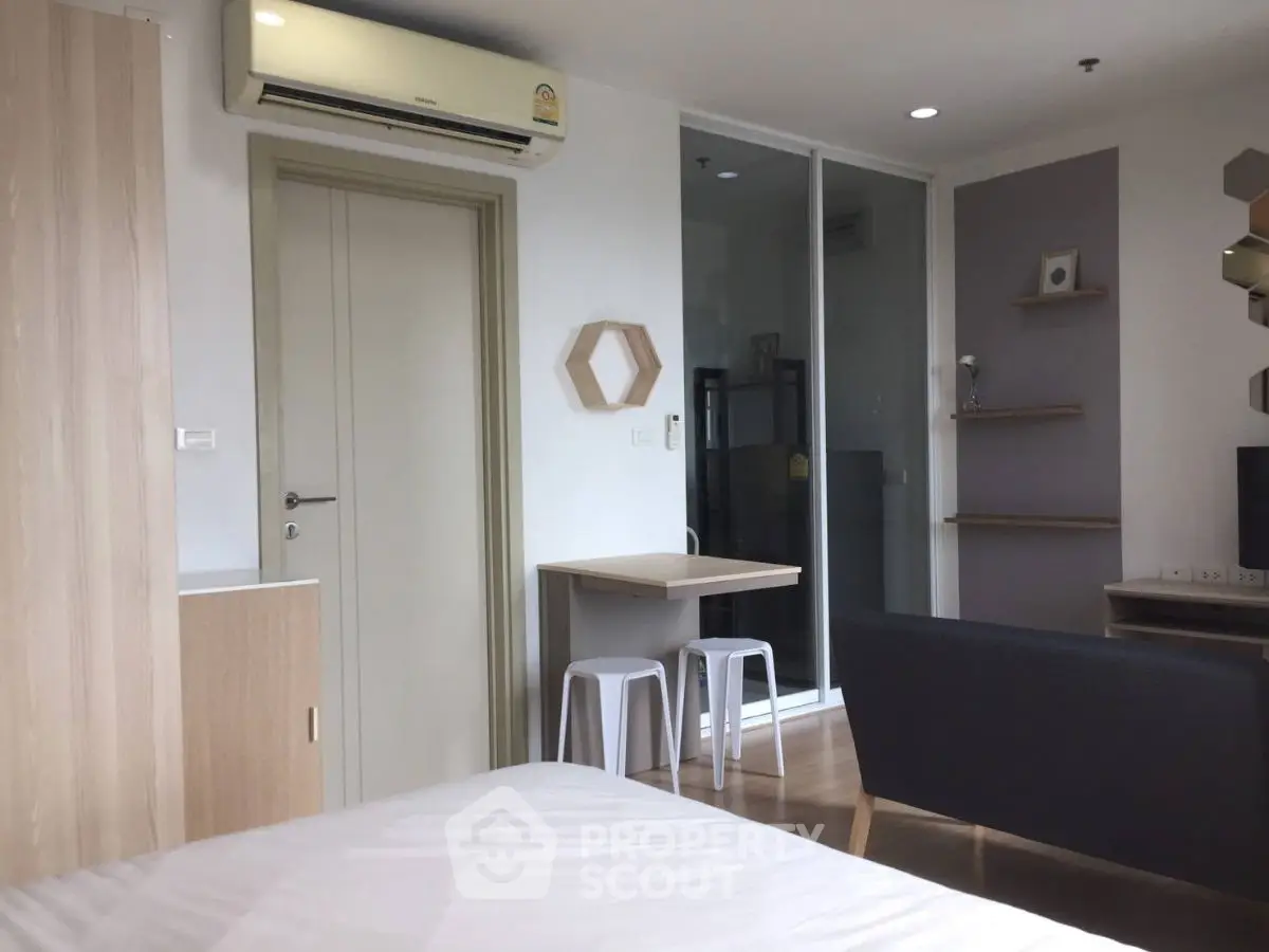Modern studio apartment with stylish decor and air conditioning, featuring a cozy seating area and compact dining space.
