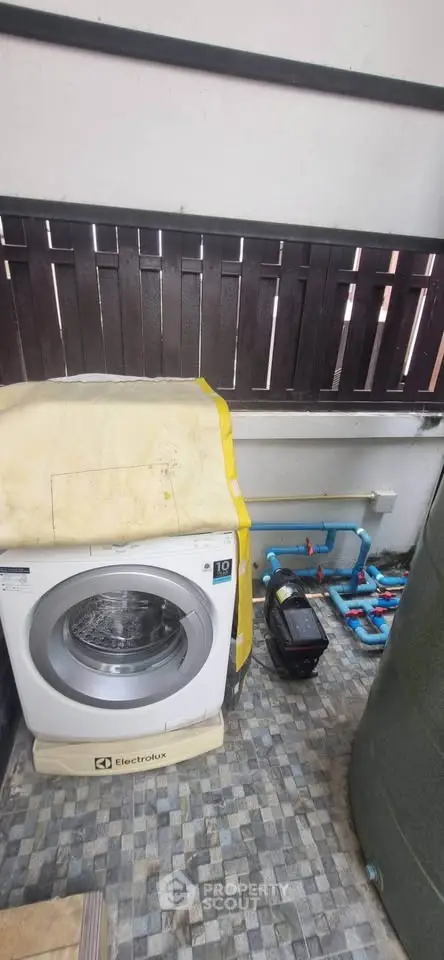 Outdoor utility area with washing machine and water pump setup