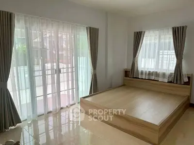 Spacious bedroom with large windows and modern wooden platform bed, offering ample natural light and serene ambiance.