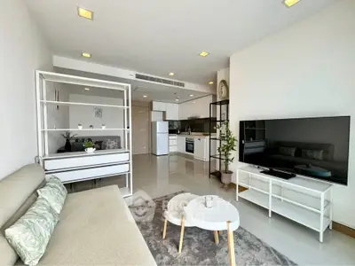 Modern living room with open kitchen, sleek furniture, and large TV