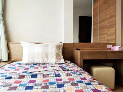 Cozy bedroom with colorful quilt and wooden furniture, perfect for a comfortable living space.