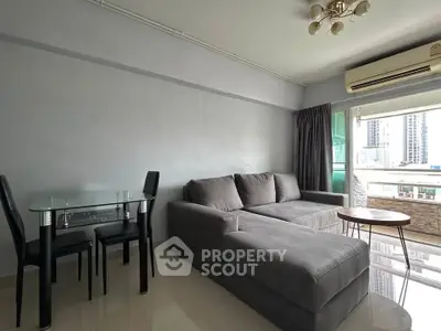 Modern living room with sleek gray sofa, glass dining table, and city view balcony.