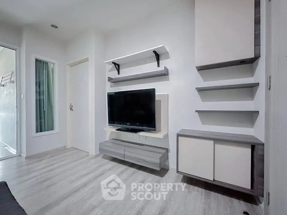 Modern living room with sleek TV unit and minimalist shelving in a bright apartment.