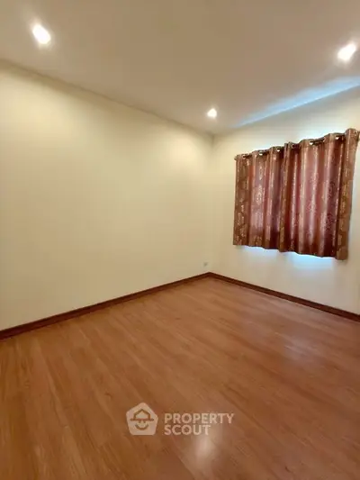 Spacious empty room with wooden flooring and elegant curtains, perfect for customization.