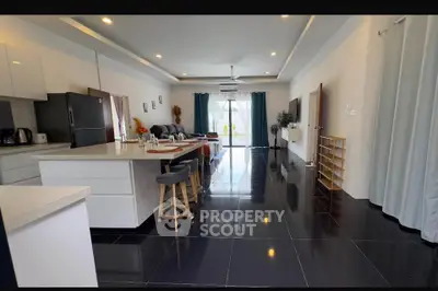 Spacious modern living room with open kitchen and sleek black tile flooring