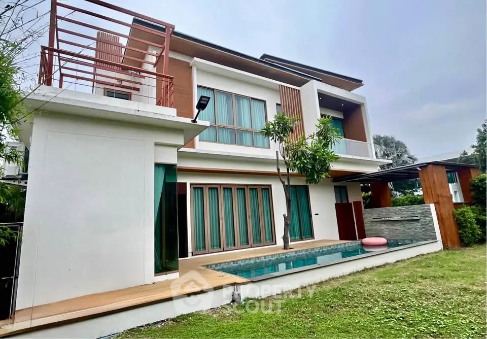 Modern two-story house with pool and garden, featuring sleek architectural design and spacious outdoor area.