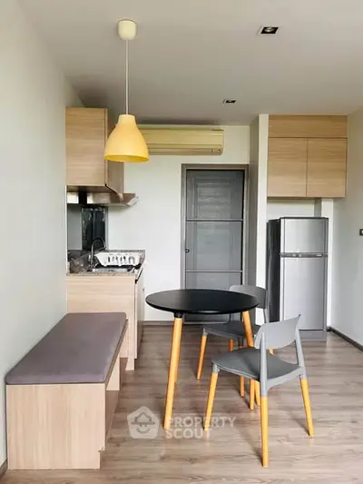 Modern kitchen with sleek design, featuring wooden cabinets, compact dining area, and stylish lighting.