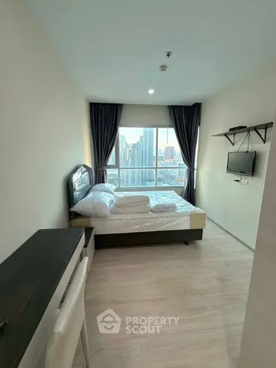 Modern bedroom with city view, featuring a cozy bed and wall-mounted TV.