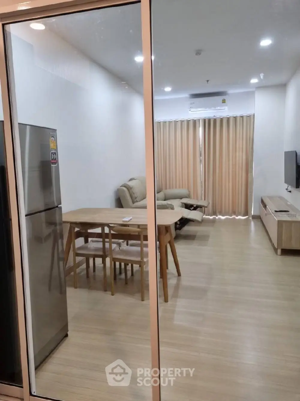 Spacious modern living room with gleaming hardwood floors, contemporary furniture, and a well-equipped kitchen, perfect for entertaining and relaxation.