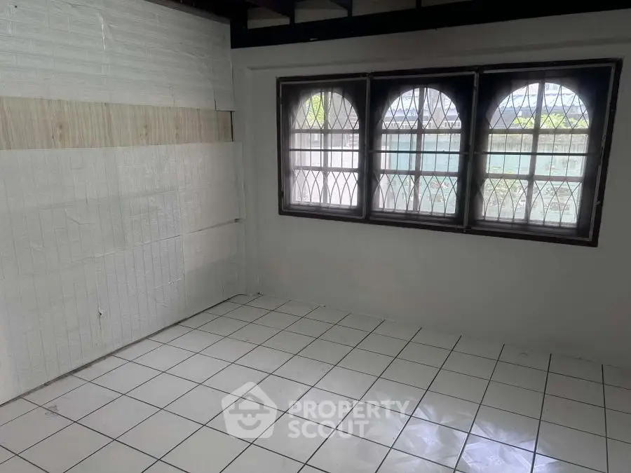 Spacious room with tiled floor and large windows, ideal for customization.