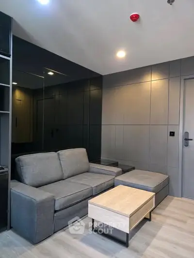 Modern living room with sleek gray sofa and stylish wooden coffee table.