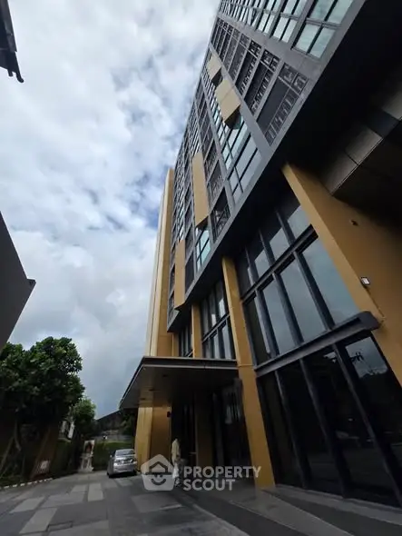 Modern high-rise building exterior with sleek design and large windows, showcasing urban architecture.