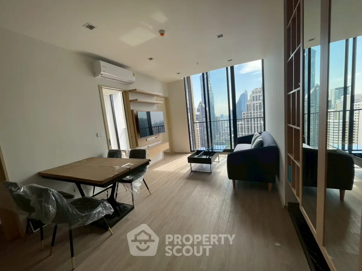 Modern living room with city view, featuring sleek furniture and large windows for natural light.
