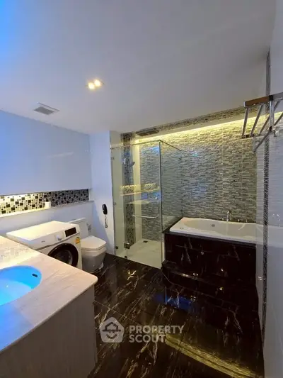 Luxurious modern bathroom with glass shower, bathtub, and washing machine in sleek design.