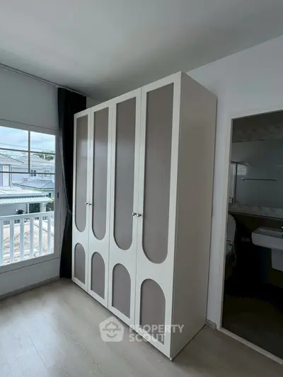 Spacious bedroom with elegant wardrobe and balcony view in modern apartment